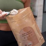 Person scooping Bare Blends Raw Cacao Fava Protein powder from the pouch